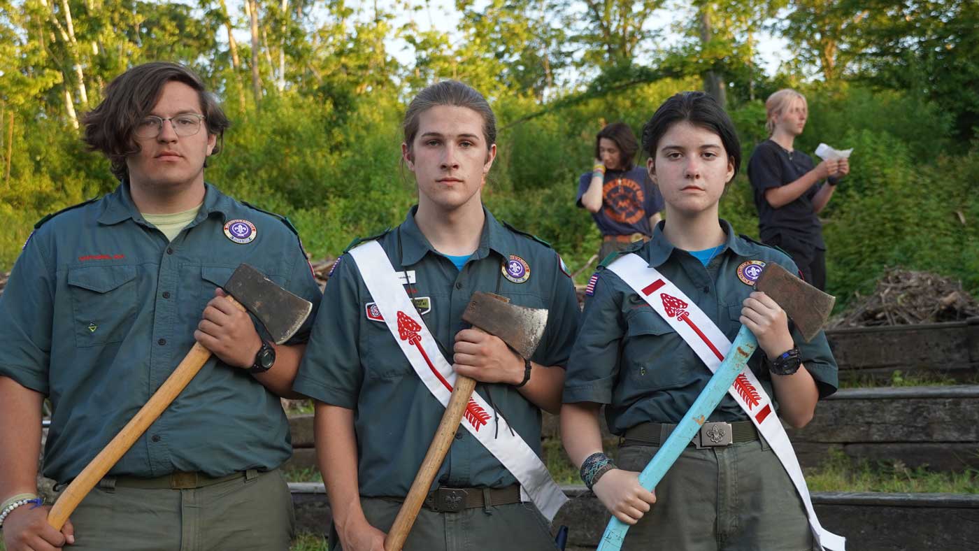 OA Scouts stand facing the camera, wearing their scout uniforms and OA sashes, holding axes near their chests