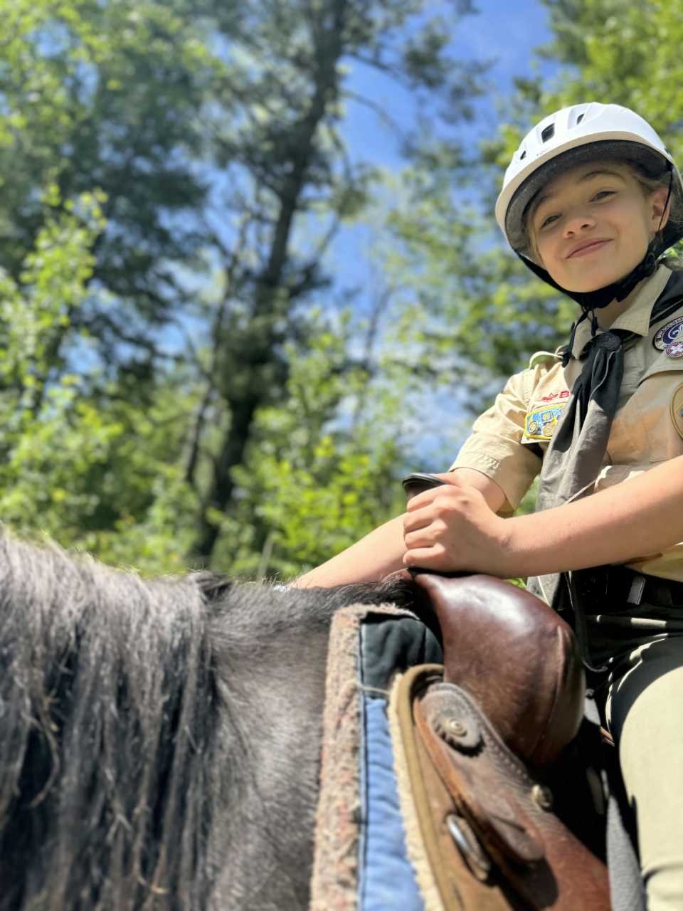 A girl scout having a great time riding a horse