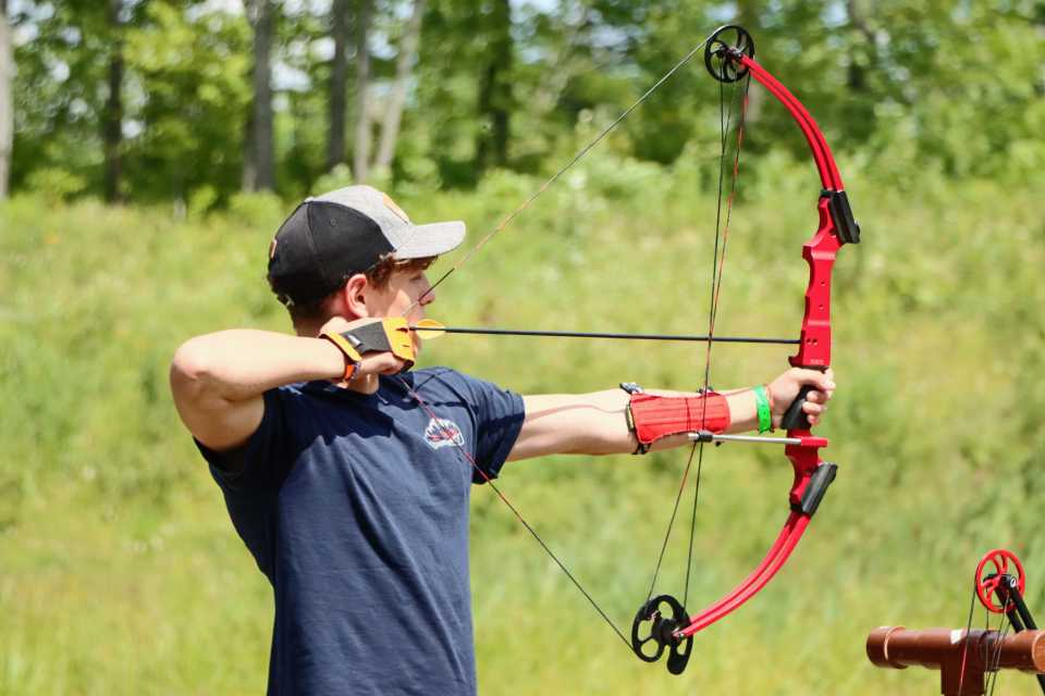 A boy readies a bow for a shot down range