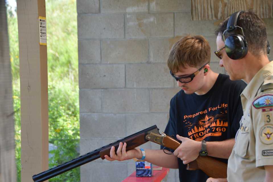 A scout looks down the chamber of a shotgun, ready to re-load it