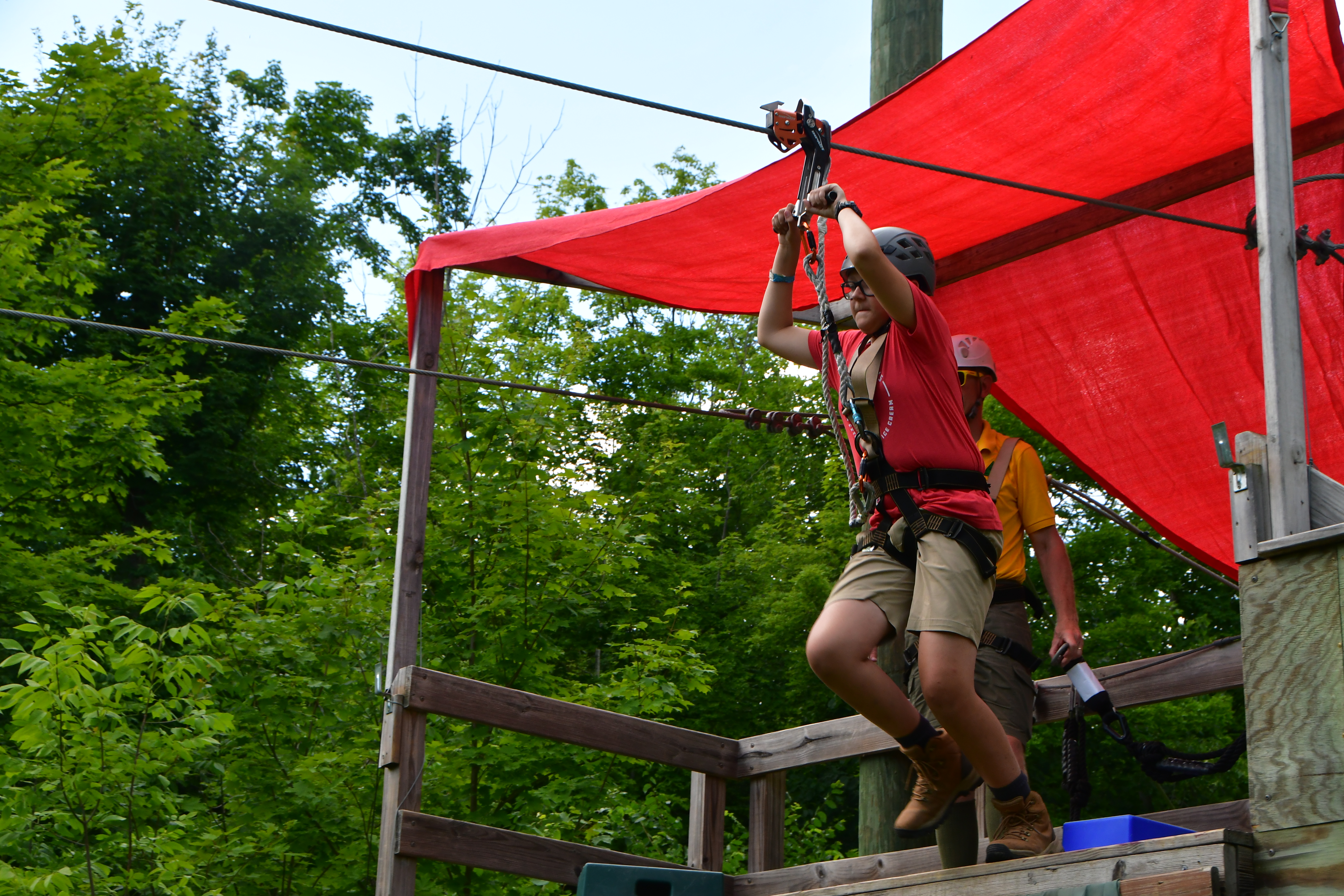 An action shot of a scout pushing off with a big jump and beginning their zip-line trip