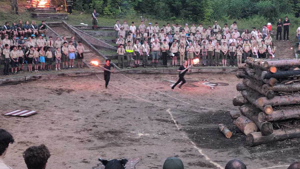 Fire Bringers carry torches across the sand towards the fire pit