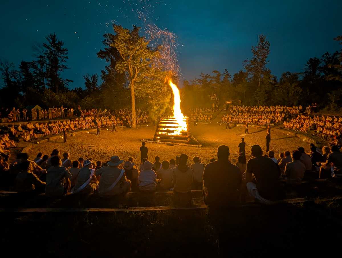 Scouts surround a huge bonfire, with a beautiful clear night sky above