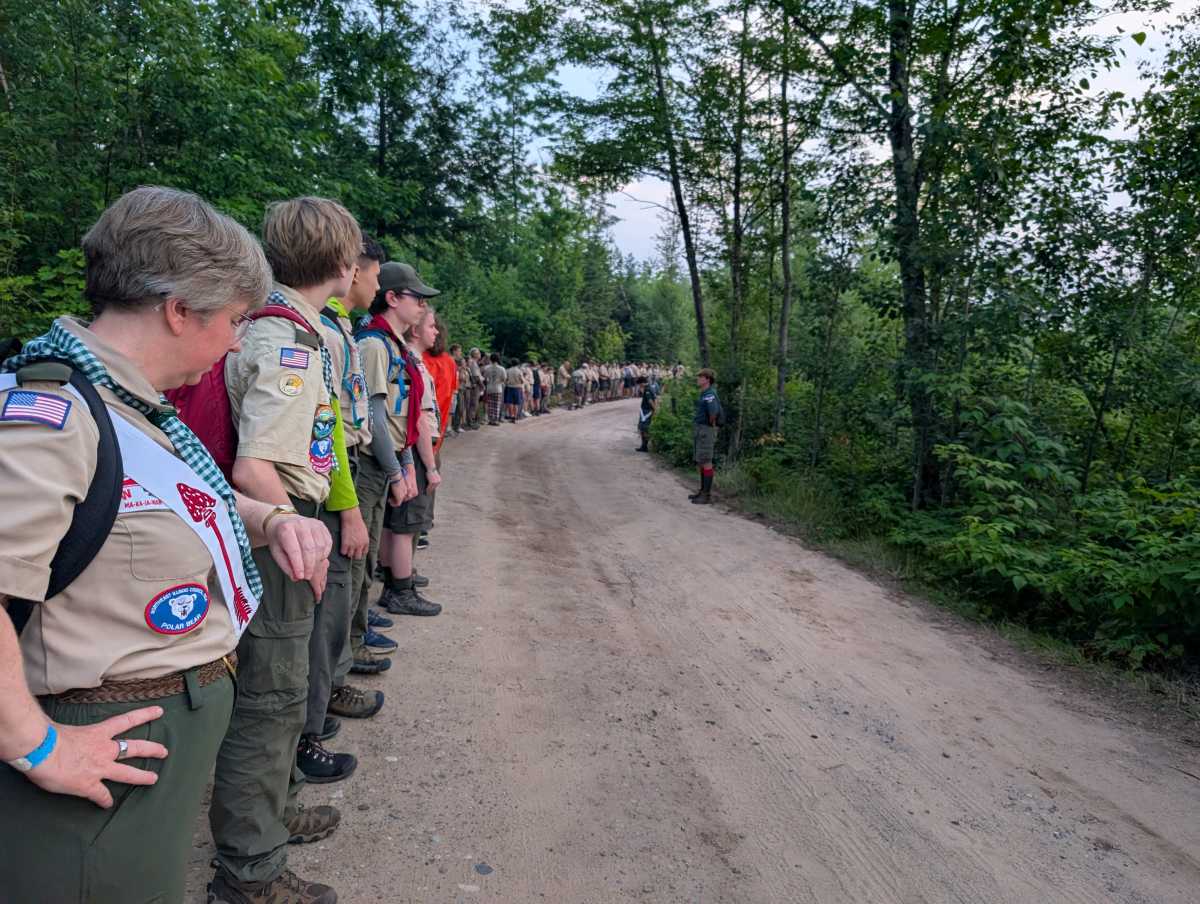 Scouts line up along a woodland trail, standing shoulder-to-shoulder