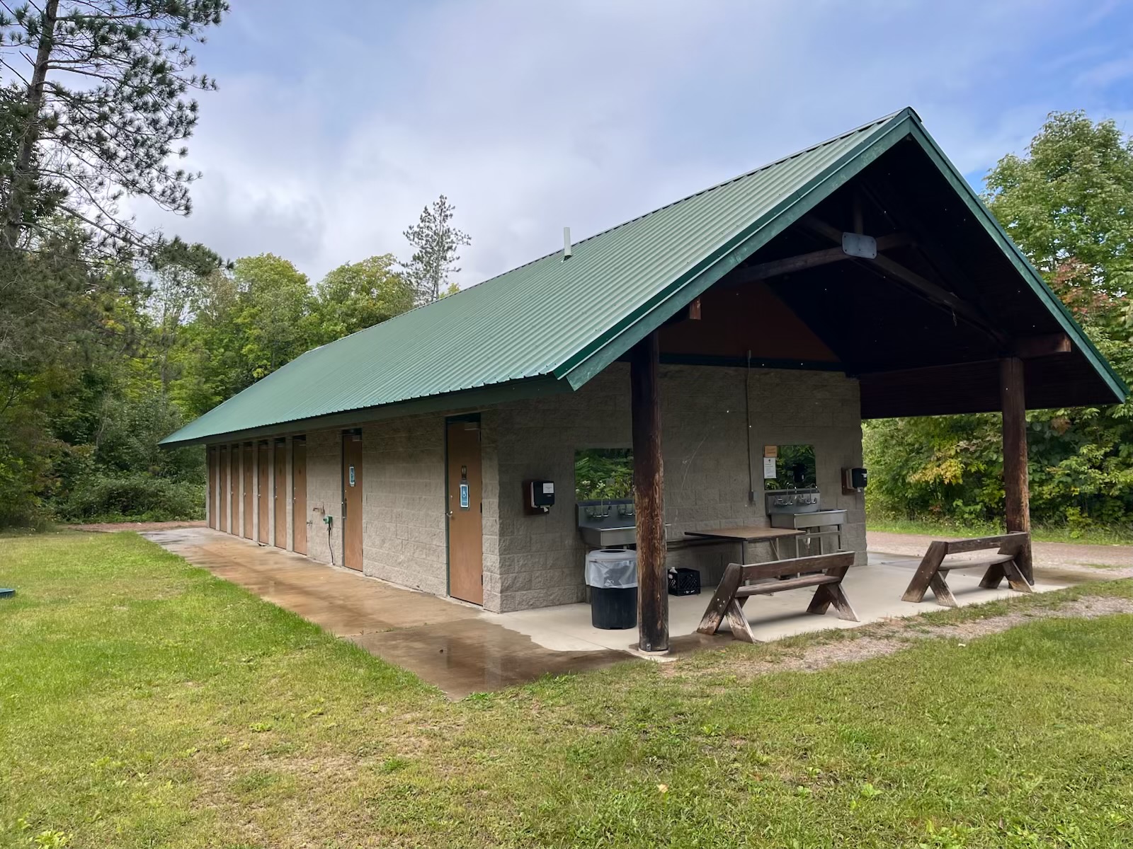 A stone building for showers and bathrooms, with a few benches and a water fountain outside.