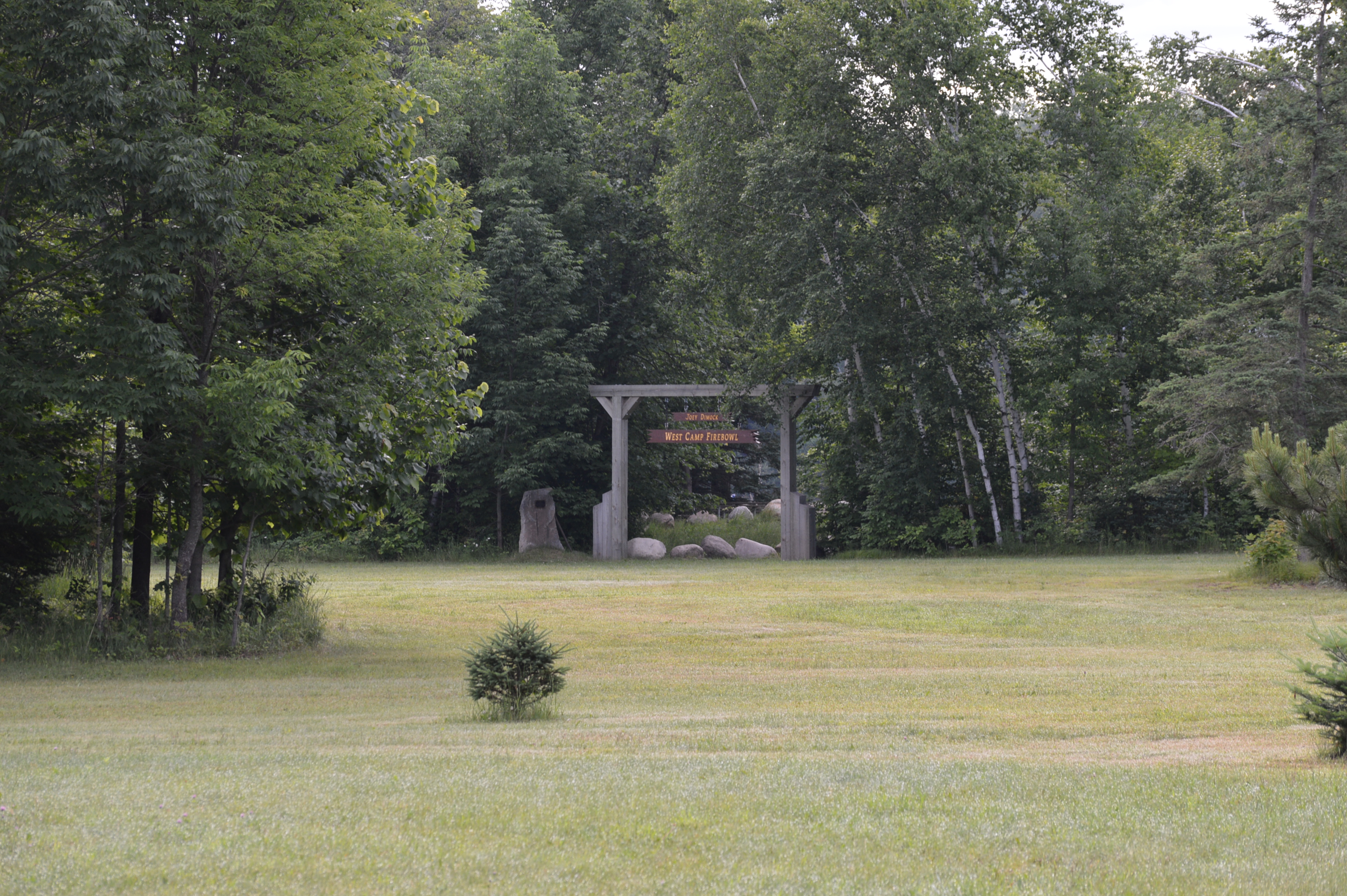 A stone sign is visible in the distance across a large mown grass field.