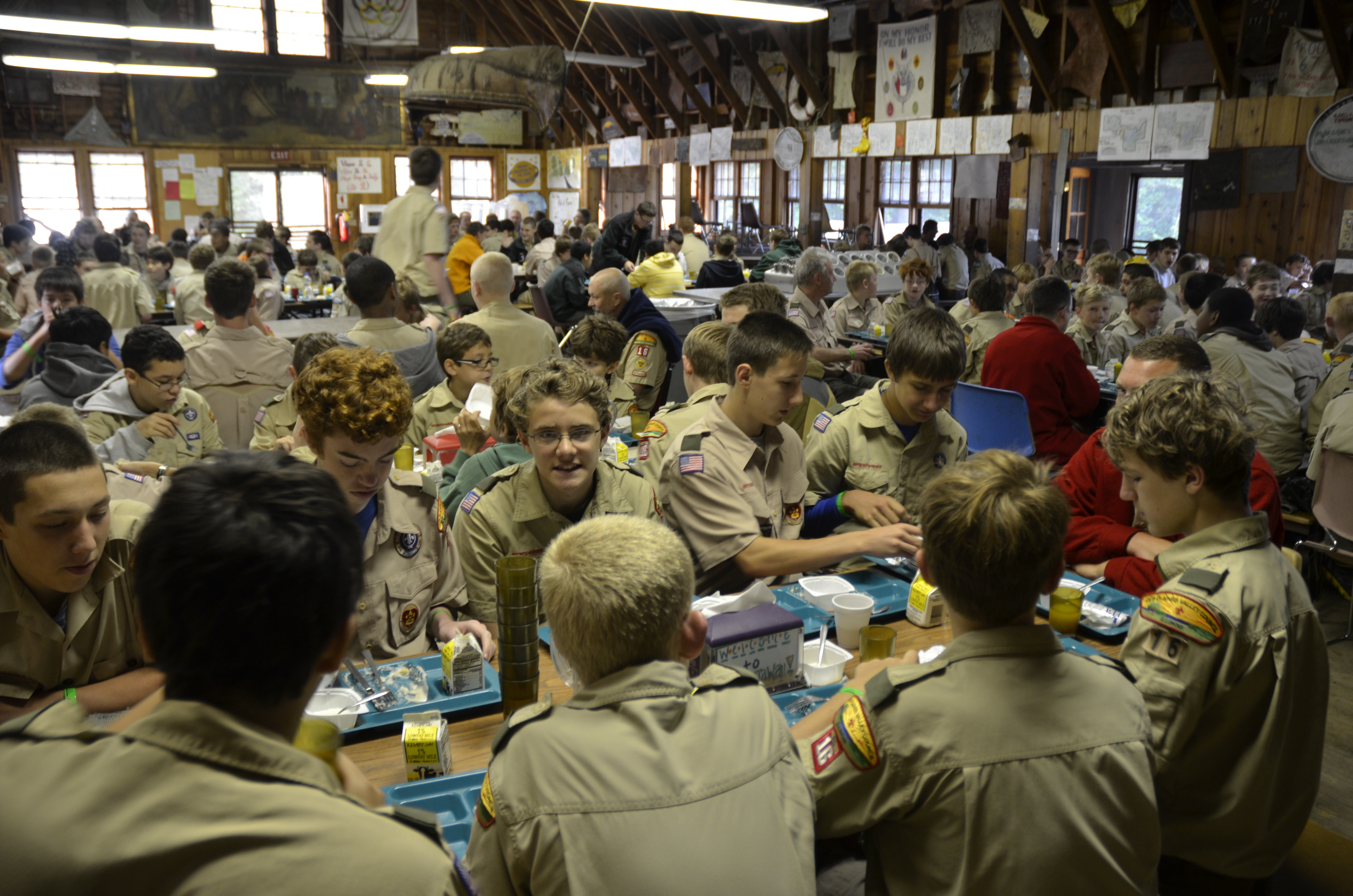 Scouts sit around a table in the dining hall, enjoying a meal