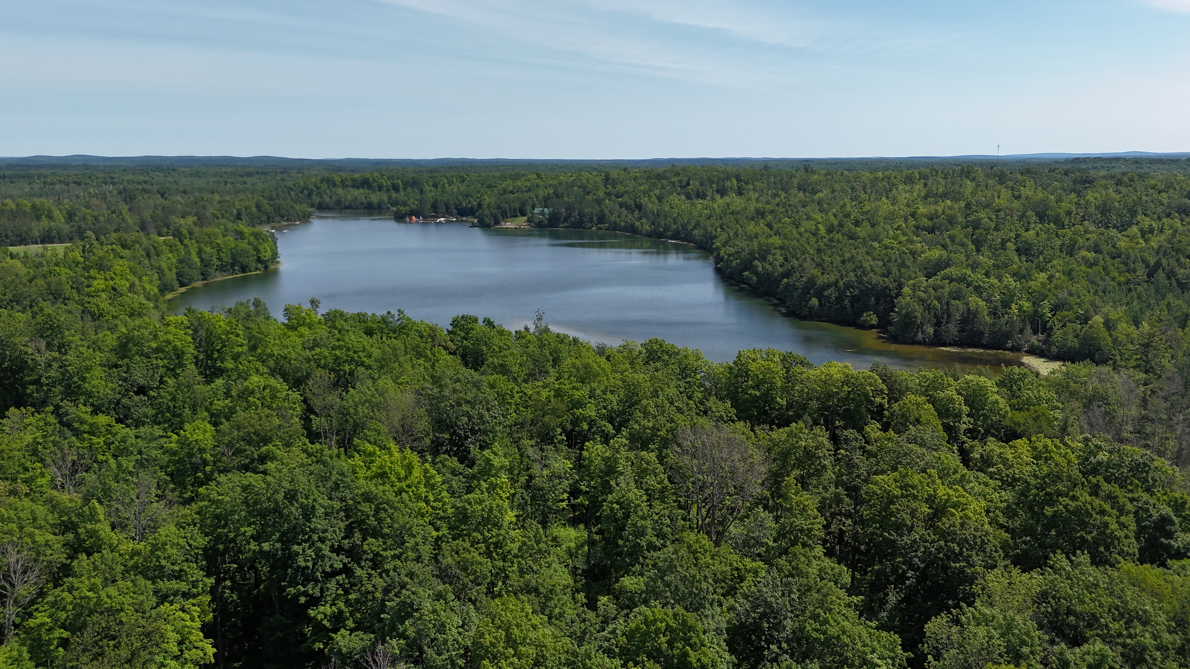 An aerial shot of Lake Killian shows the forest line of lush green riding directly up to the coast of the deep blue waters.