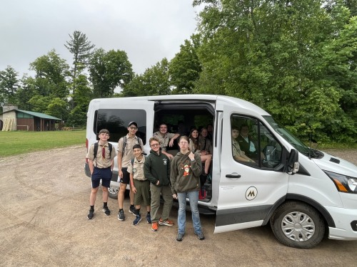 Scouts stand in front of a "shuttle-bus" van.